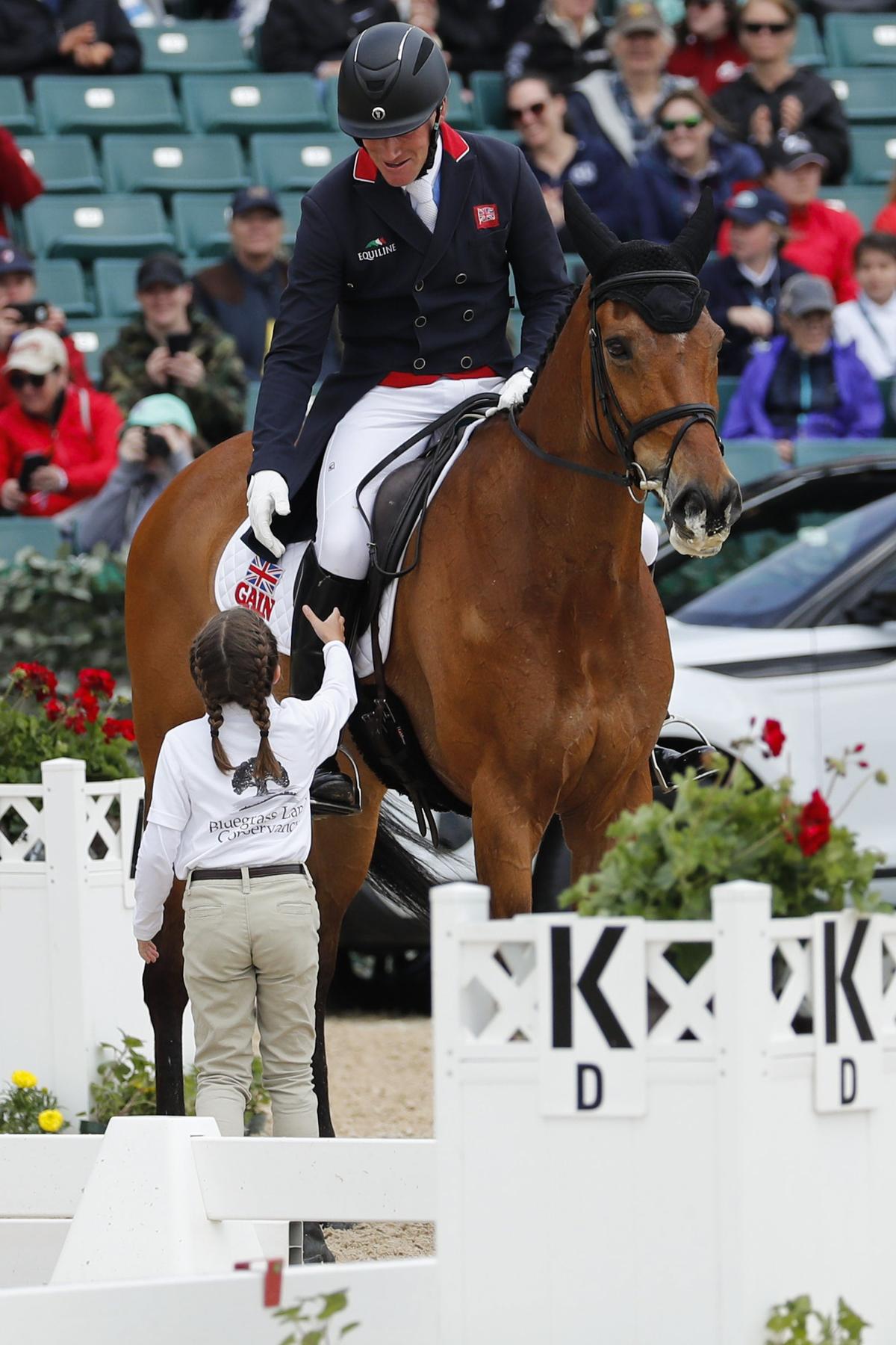 Oliver Townend (GBR) riding Cooley Master Class greeted Pony Club volunteer Suzanna Hall during dressage during The Land Rover Kentucky Three-Day Event at the Kentucky Horse Park in Lexington, Ky., Friday, April 26, 2019. The 2021 event may have to cancel if spectators will not be allowed. Current coronavirus restrictions from the sport’s governing body don’t allow for spectators.