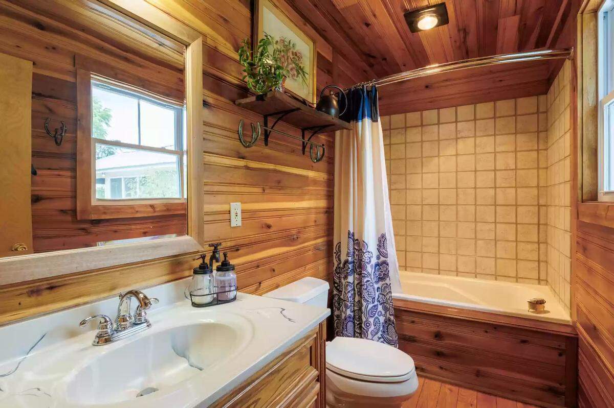A bathroom connected to the upstairs bedroom at 4351 Bethel Road. The bathroom has the same warm wooden design as the bedroom it connects to. 