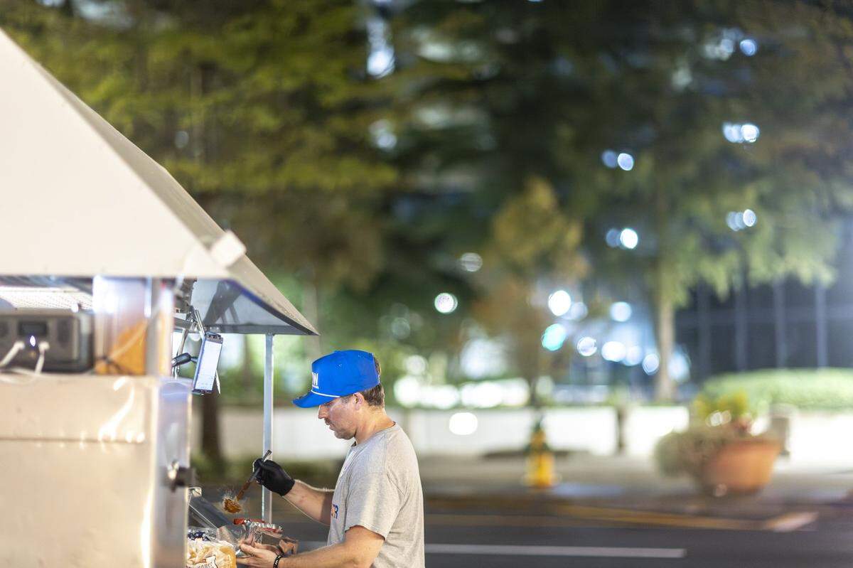 Chris Price, the owner and operator of Big Blue Wiener, prepares a hot dog for a customer at his stand near Henry A. Tandy Centennial Park in downtown Lexington, Ky., in the early hours of Sunday, Sept. 14, 2025.