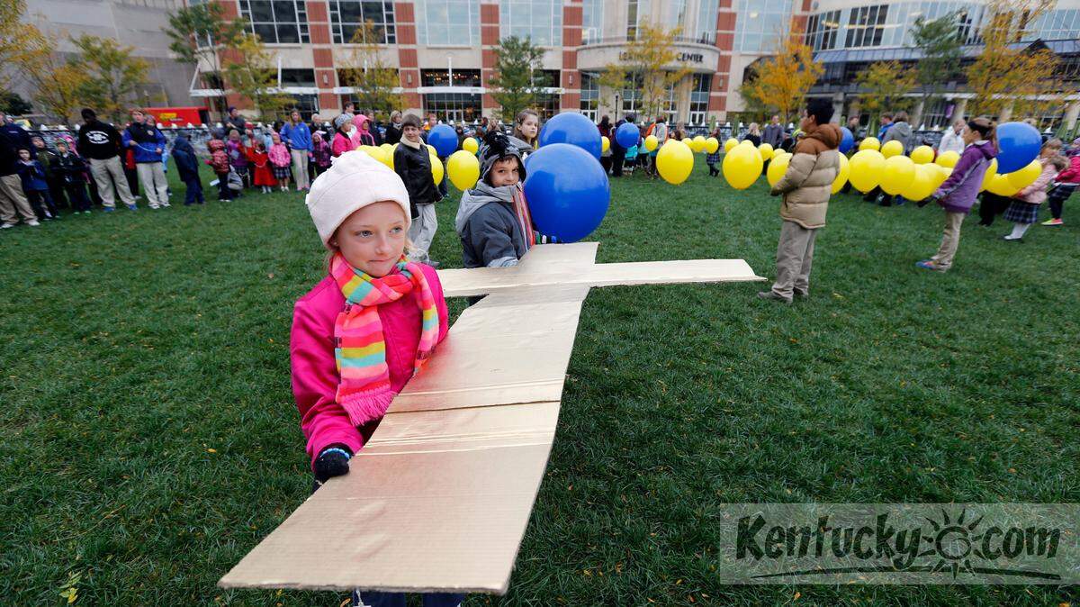 8-year-old 3rd grader Kylie Stephenson, front, and 11-year-old 6th grader, Ethan Elbert, back, held a cross during a public rosary in Triangle Park in Lexington, Ky., Thursday, October 24, 2013. Sts. Peter & Paul students (K-8) led by Bishop Ronald Gainer and members of the Knights of Columbus, marched in a rosary procession from the school to Triangle Park in a celebration marking their 100 years as a Catholic school. At the end of the procession, a 75 foot rosary made of balloons was released from the middle of the park. Photo by Charles Bertram | Staff