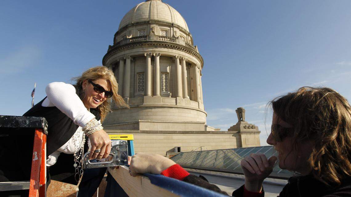 Inauguration decor coordinator Carol Mitchell, left, and Sara Osborne made a banner on the rooftop of the Capitol on Friday. Bob Stewart, executive director for Gov. Steve Beshear's inaugural on Tuesday, said the celebration should cost less than $400,000, about half of the cost for Beshear's first.    