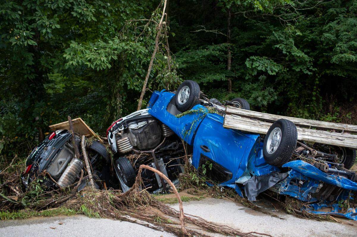Vehicles are piled up along the side of the road after being carried down street by flooding in Perry County, Ky., Friday, July 29, 2022.