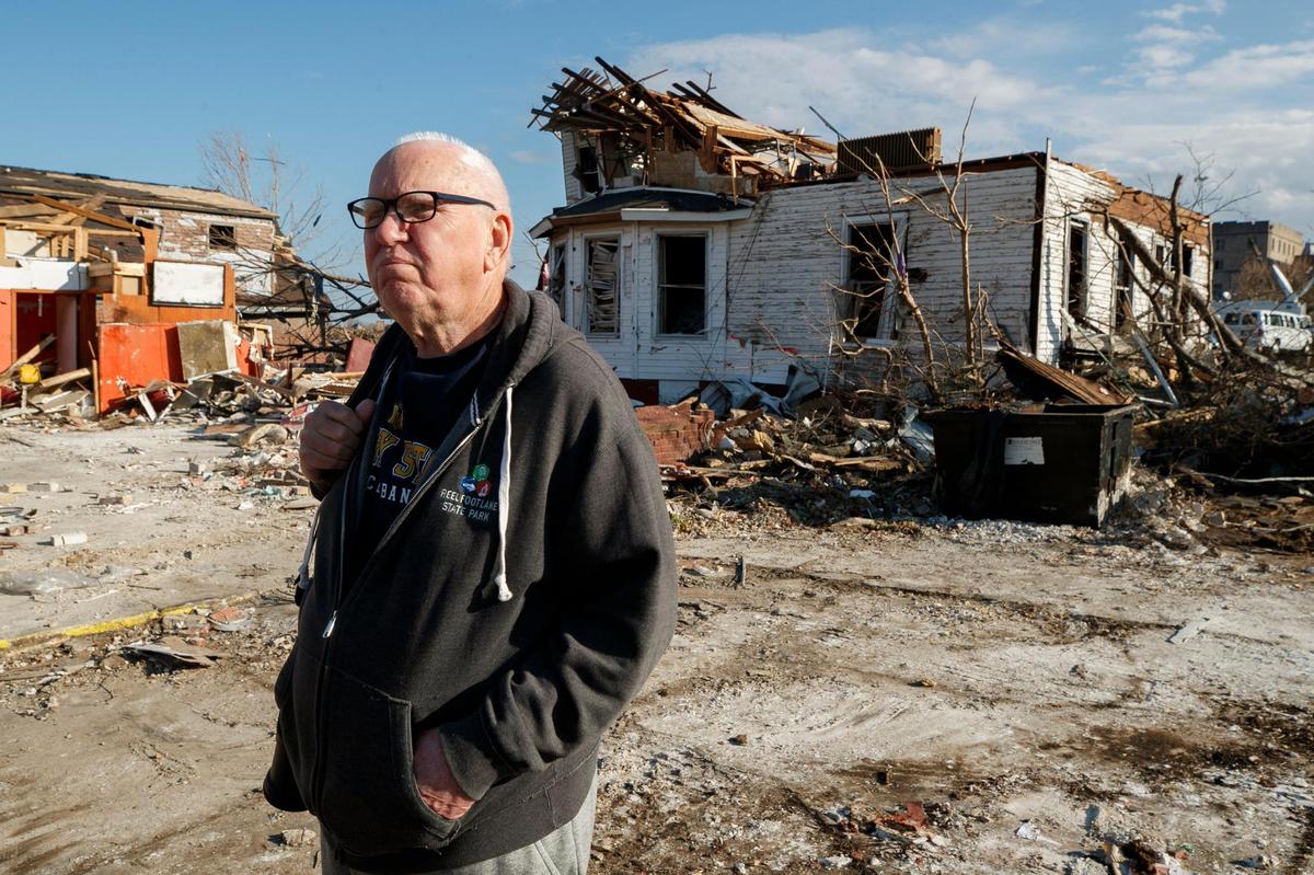 Retired history professor and Mayfield native Berry Craig, of Arlington, Ky., examines damaged buildings near a former grocery store near downtown Mayfield., Ky., Tuesday, Dec. 14, 2021. Although Craig moved from Mayfield decades ago he still feels deeply attached to the town.