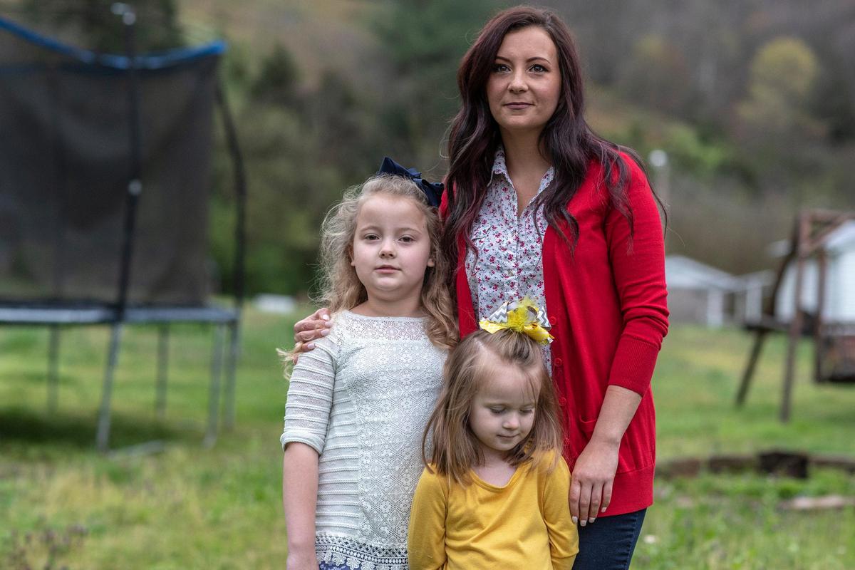 Ariel Johnson poses for a portrait with her daughters, Aubrey Lawson, 7, and Allie Walker, 3, outside their home in Grethel, Ky., on Wednesday, April 1, 2020. Johnson is a bartender who lost recently lost her job.