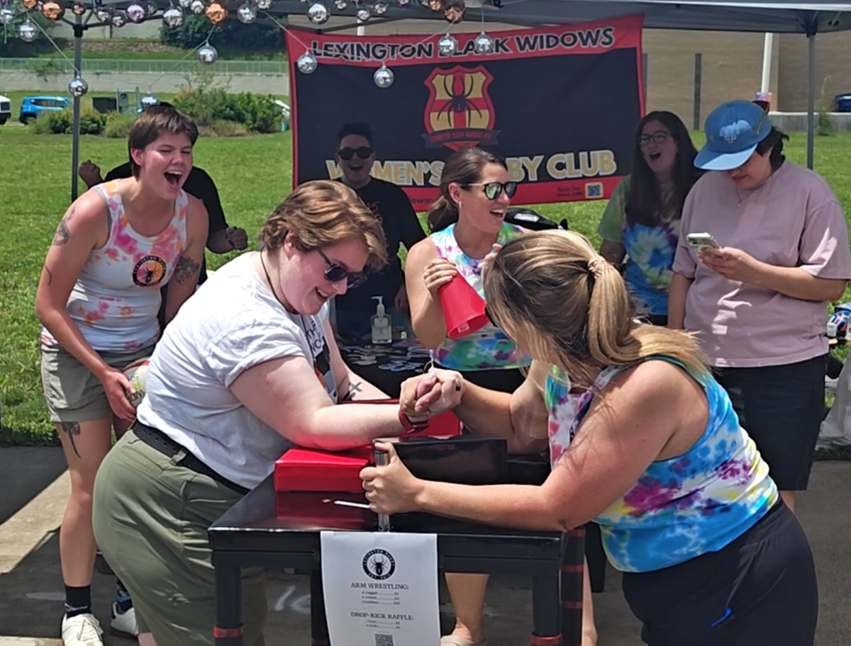 Competitors battle in one of the ongoing arm wrestling matches in front of the Lexington Black Widows rugby club booth at the 2026 Lexington Pride Festival.
