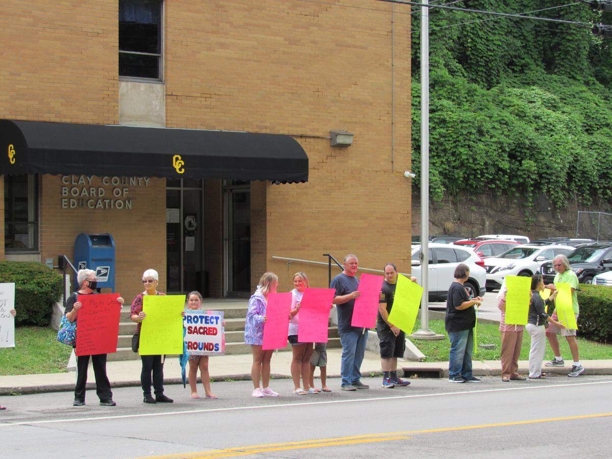 People opposed to a plan by the Clay County Board of Education to move graves from a family cemetery overlooking an elementary school protested outside the board office in Manchester on July 8, 2021.