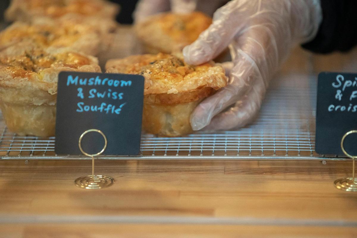 Narimane Kayed Mahamoud, a bakery assistant, places mushroom and Swiss soufflés on racks for sale.