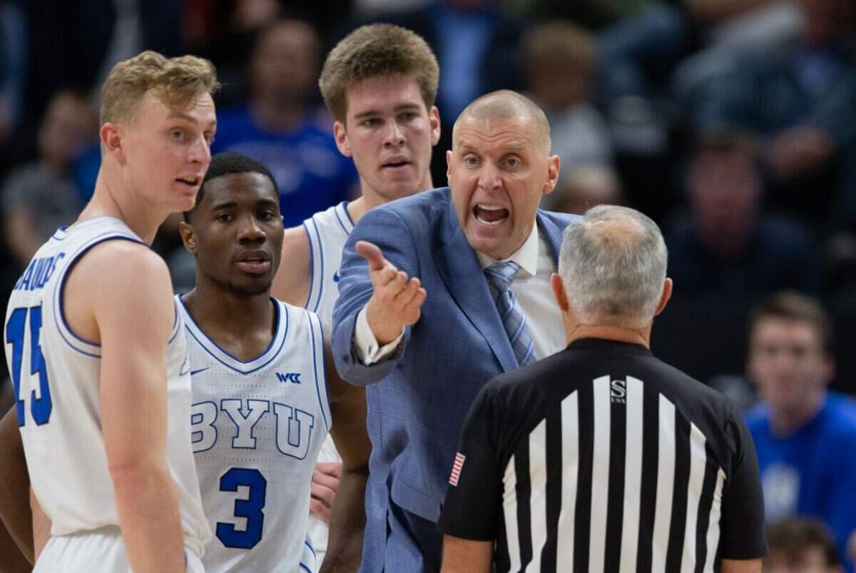 SALT LAKE CITY, UT - DECEMBER 3: Mark Pope head coach of the Brigham Young Cougars argues a call with referee Randy McCall during the second half of their game against the South Dakota Coyotes at the Vivint Arena December 3, 2022 in Salt Lake City, Utah. Richie Saunders #15, Rudi Williams #3 and Noah Waterman #0 of the Brigham Young Cougars watch from the huddle.(Photo by Chris Gardner/ Getty Images)