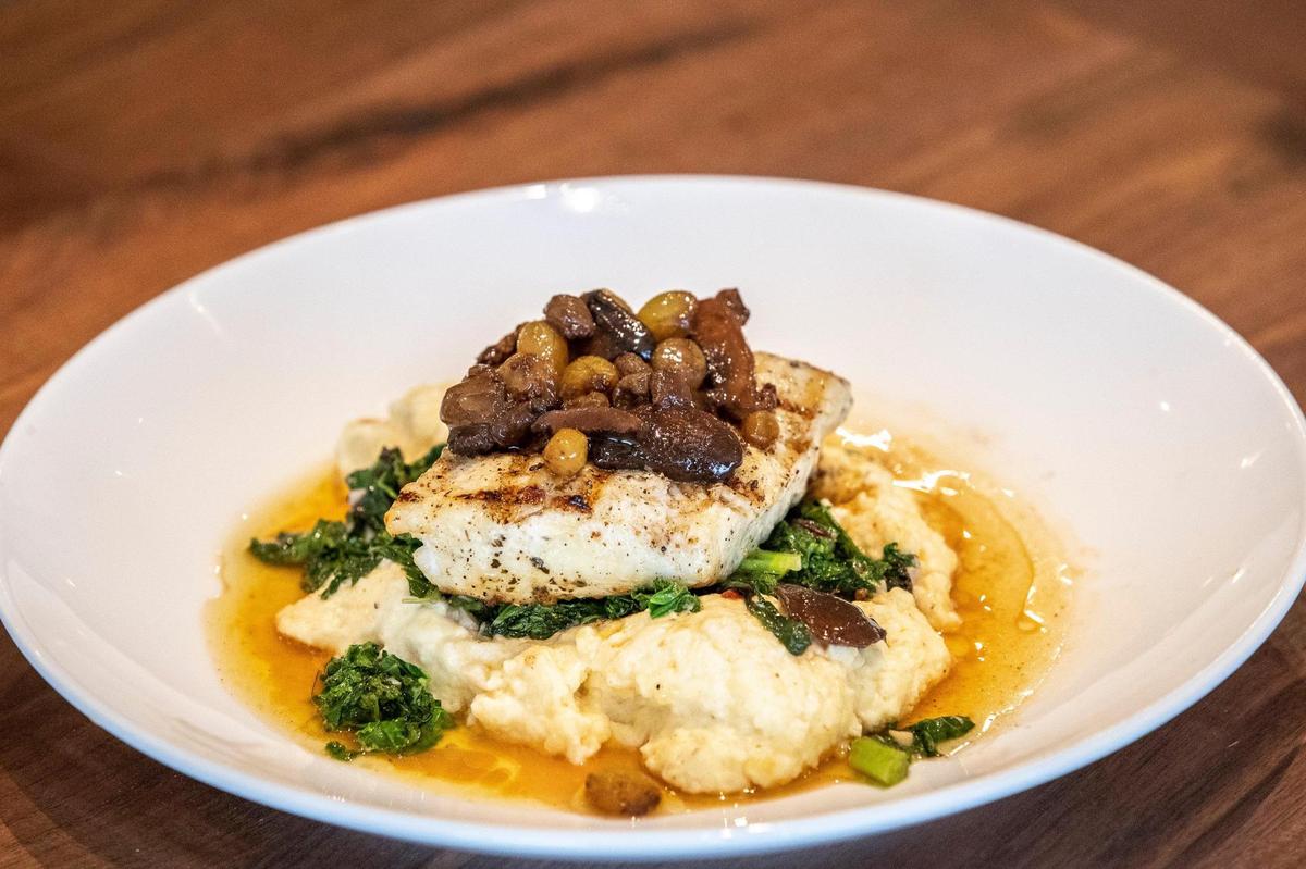 Halibut, with polenta, sauted greens, criminology and shiitake mushrooms, gold rosins and lemon balsamic brown butter, at Bella Cafe & Grille.