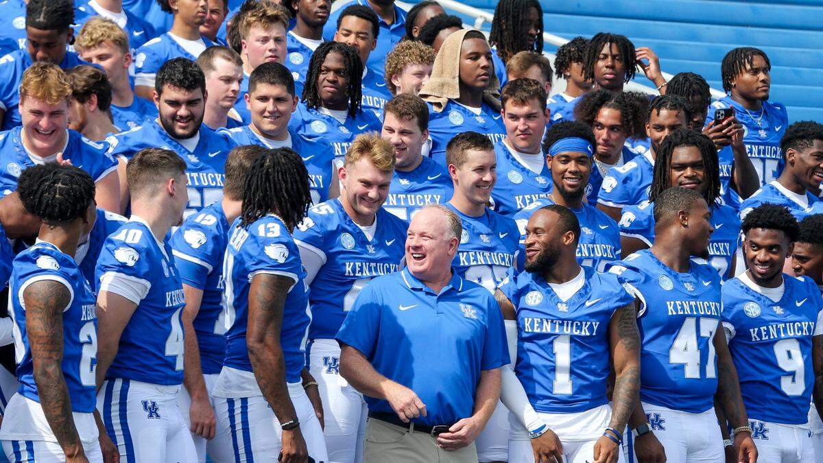 Kentucky head coach Mark Stoops, center, laughs with his players as they prepare for a team photo during Media Day at Kroger Field on Friday.