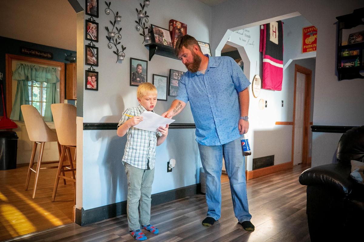 Brandon Humphries, of Rineyville, helps is stepson, Anders Davenport, 7, with his homework at their home. Last month Humphries was mistakenly issued a summons to appear in front of a Fayette County judge for for alleged abuse and neglect of one of his younger daughters.