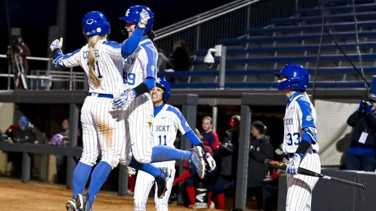 Erin Coffel (21) was met at home plate by teammate Kayla Kowalik (99) after Coffel’s three run home run put Kentucky in front in the sixth inning of its home-opening victory over Dayton on Wednesday night.