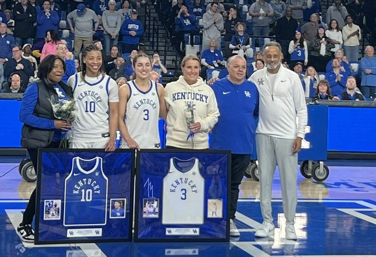 Kentucky coach Kenny Brooks, right, recognized Dazia Lawrence (10), Georgia Amoore (3) and their parents during Senior Day festivities in Memorial Coliseum.