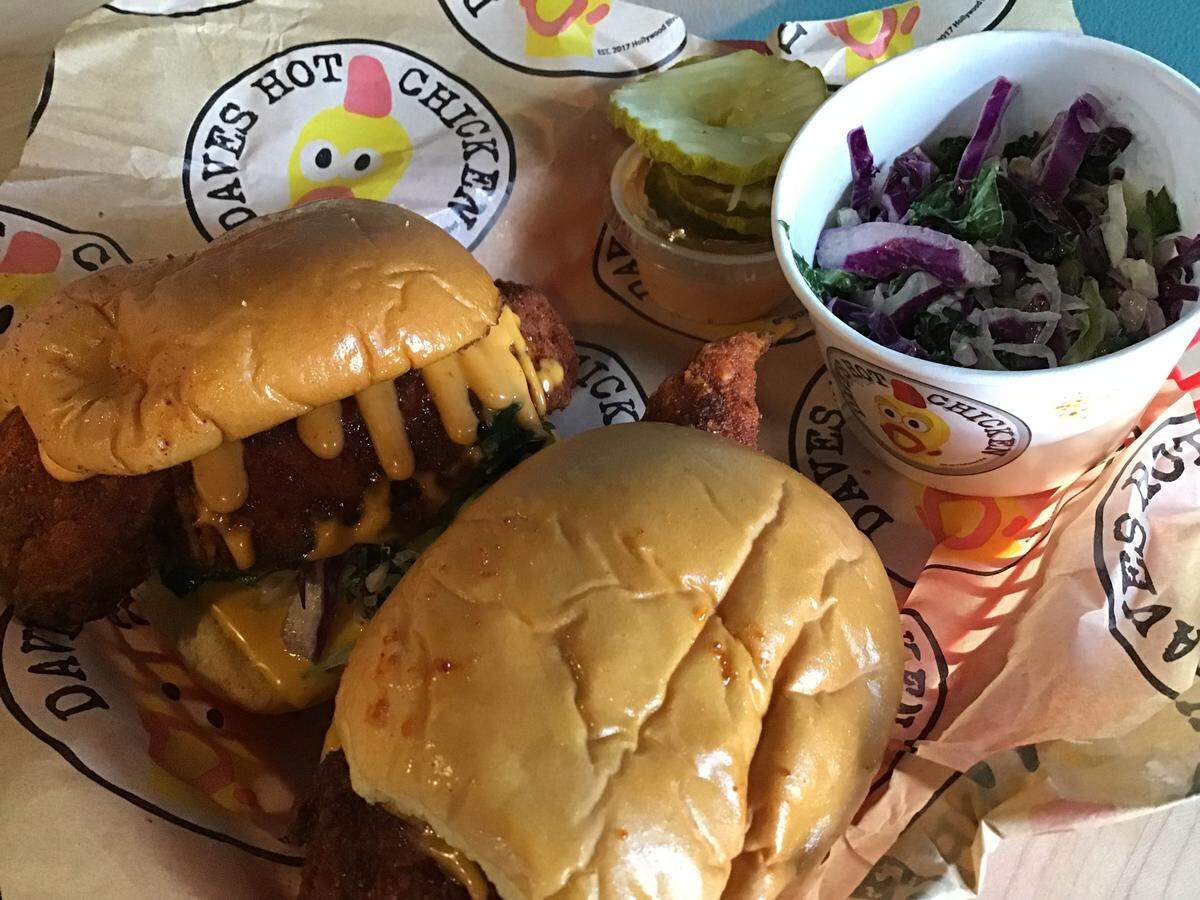 The menu at Dave’s Hot Chicken includes sliders, with large chicken pieces slathered in sauce. You get to pick your heat level, from no spice to “reaper,” an ultra hot level. Sides include kale slaw.