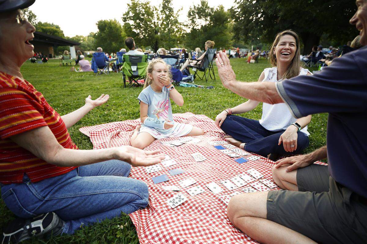 Izzy Balsamo, 9, of Charlotte, N.C., center, reacts while playing cards with her grandparents Anne Graham, left, and, Stephen Graham, right, both of Lexington, Ky., and mother Zoe Balsamo, also of Charlotte, N.C., during the Big Band & Jazz concert series at Ecton Park in Lexington in 2019.