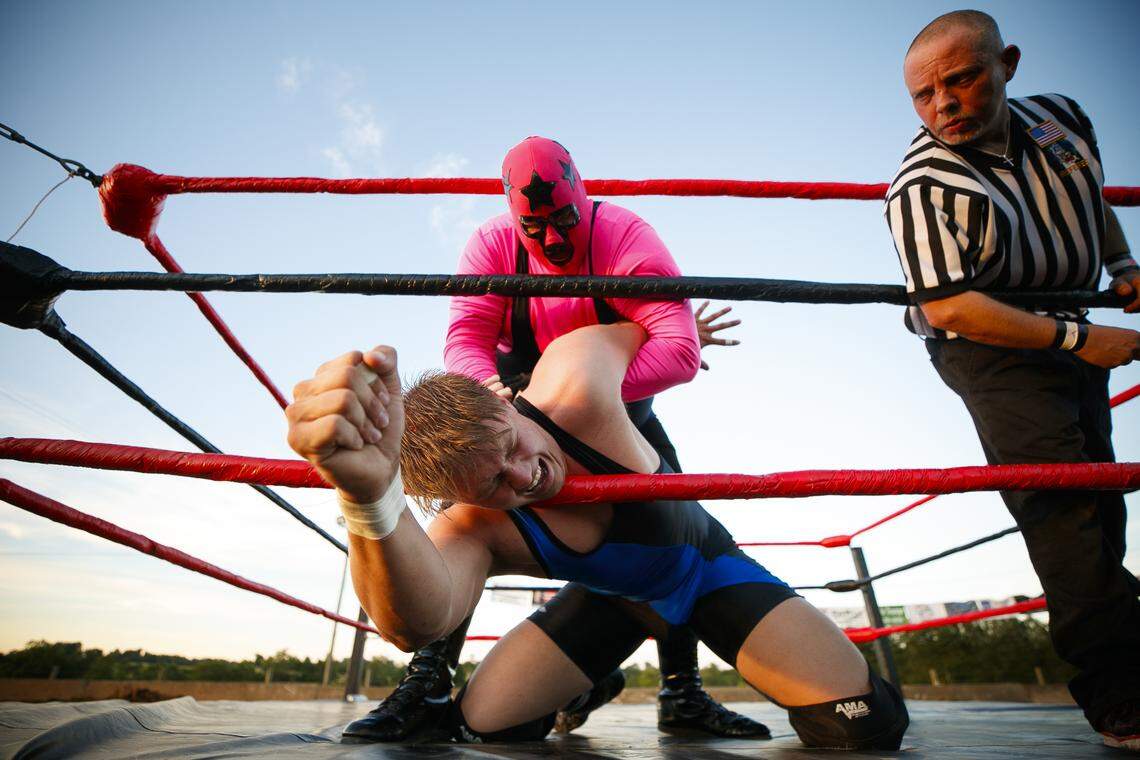 United States Wrestling Federation wrestlers Masked Superstar, top, and Carson Drake, who would only give their stage names, perform for the crowd as referee John Conway, of Danville, Ky., right, looks on at the Garrard County Fair in Lancaster, Ky., Tuesday, June 25, 2019. The Garrard County fair continues through Saturday.