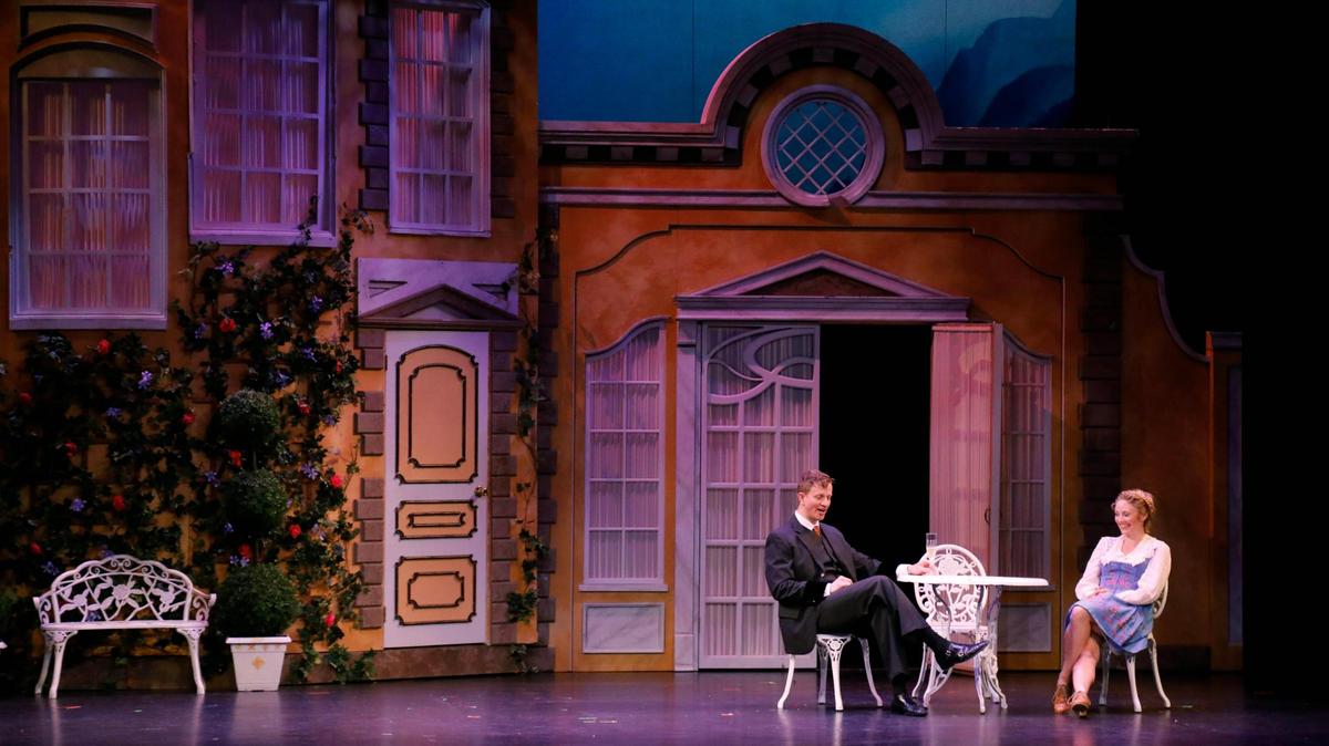 From left, Jeremy Landon Hays as Captain von Trapp and Hayley Podschun as Maria Rainer sit at a table together on Wednesday, July 11, 2023 at the Lexington Opera House in Lexington, Ky.