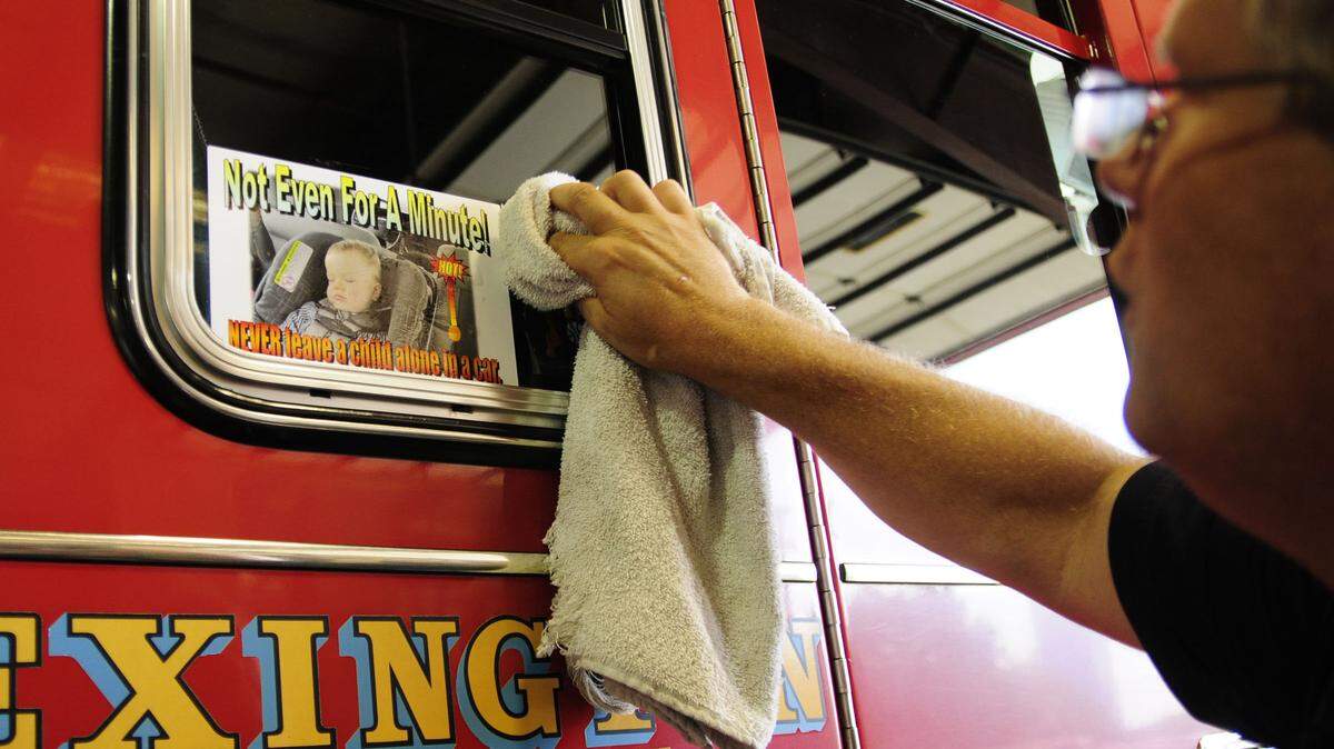 Firefighter John Davis, 49, of the Lexington Fire Department applied a warning sticker to a Lexington fire truck at Central Fire Station on East Third Street last summer. The sticker was part of a campaign to prevent heat deaths.