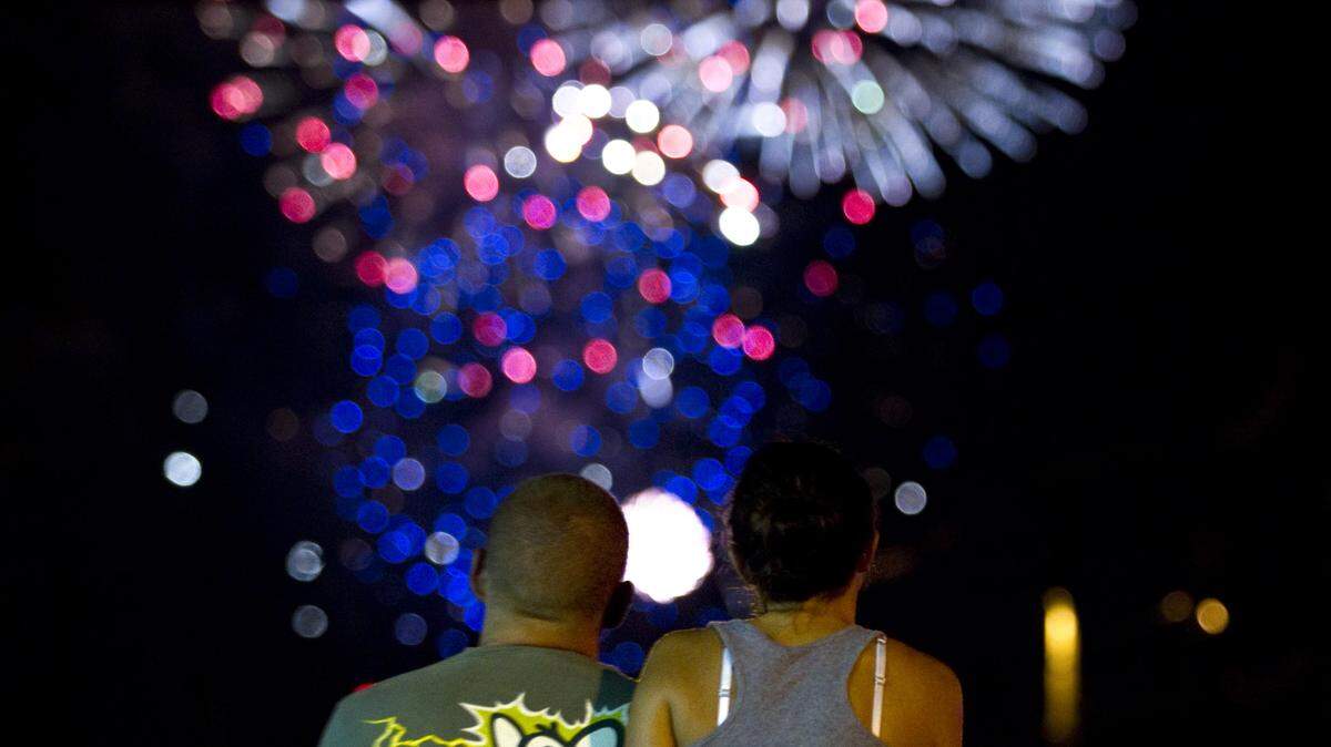 Ryan Moore, left and Rebecca Krebs, looked on as  Lexington's fireworks fly high overhead near the Meadowthorpe shopping center  on Wednesday July 4, 2012 in Lexington, Ky.