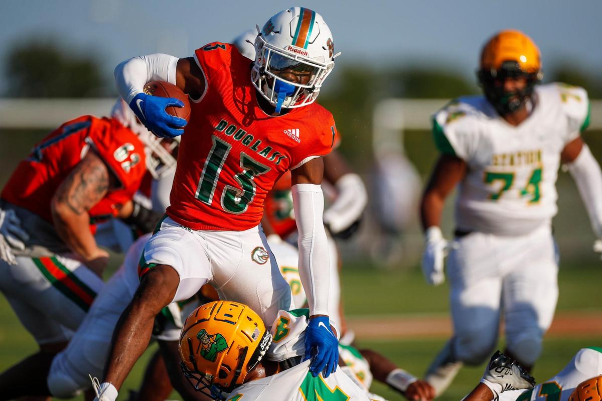 Frederick Douglass’s Ty Bryant (13) tries to avoid a Bryan Station tackle during the first half of the Broncos’ 52-7 win over their city rival at Frederick Douglass High School on Friday.