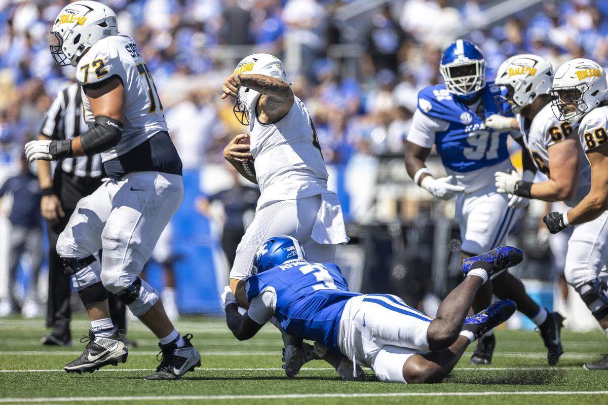Kentucky Wildcats linebacker Alex Afari Jr. (3) wraps up Toledo Rockets quarterback Tucker Gleason (4) during a game at Kroger Field in Lexington, Ky., on Saturday, Aug. 30, 2025. 