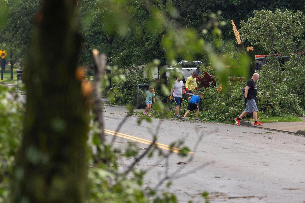 Residents work to remove trees, branches and other debris along Sandersville Road in Lexington, Ky., on Thursday, June 26, 2025, following a storm with strong winds.