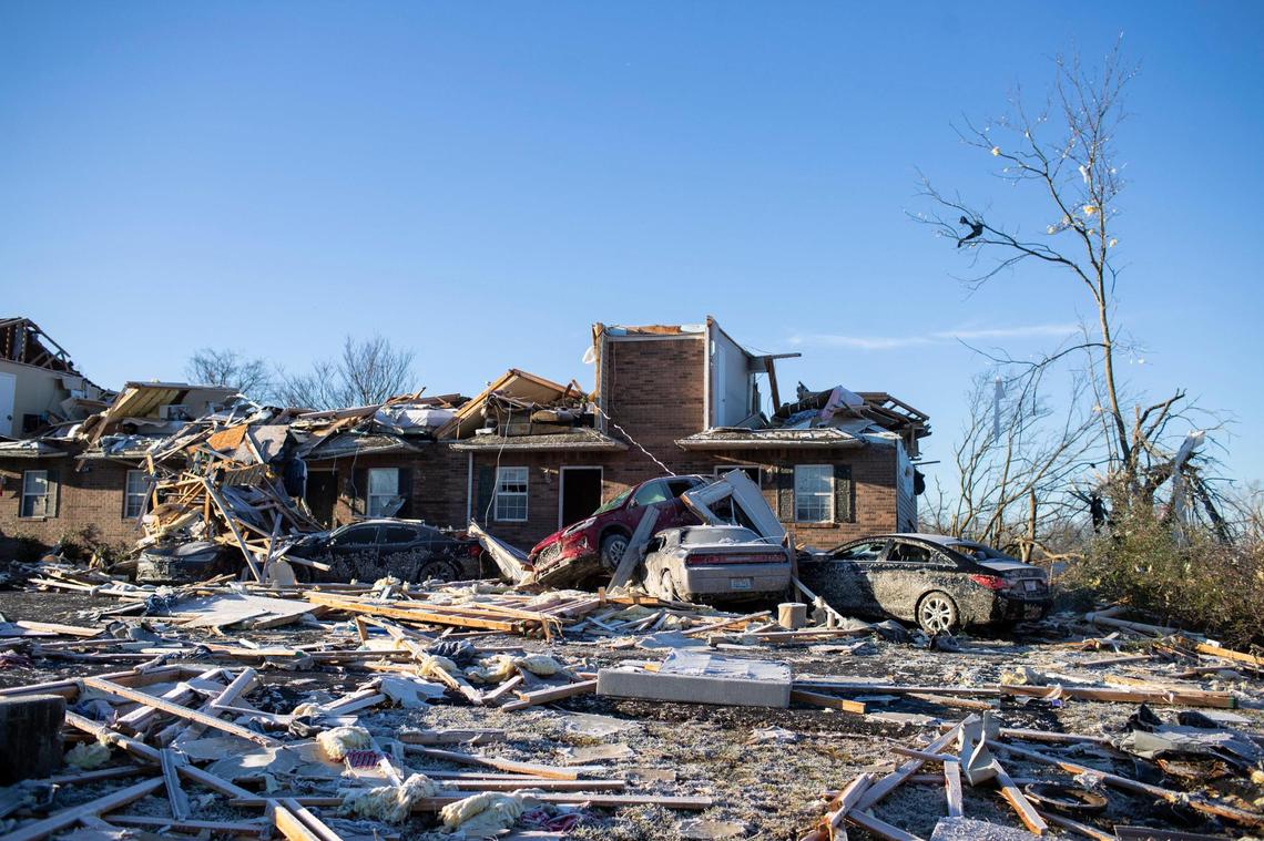 Damaged vehicles and debris from a tornado that passed through neighborhoods sit up against a damaged apartment complex near Russellville Road in Bowling Green, Ky., Sunday, December 12, 2021.