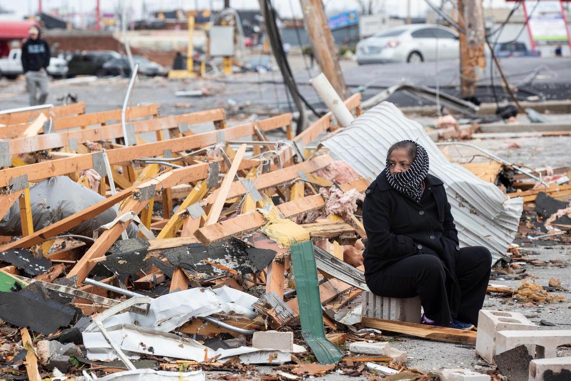A woman sits on debris of a of a building damaged by a tornado that came through the 31W By-Pass in Bowling Green, Ky., Saturday, December 11, 2021.