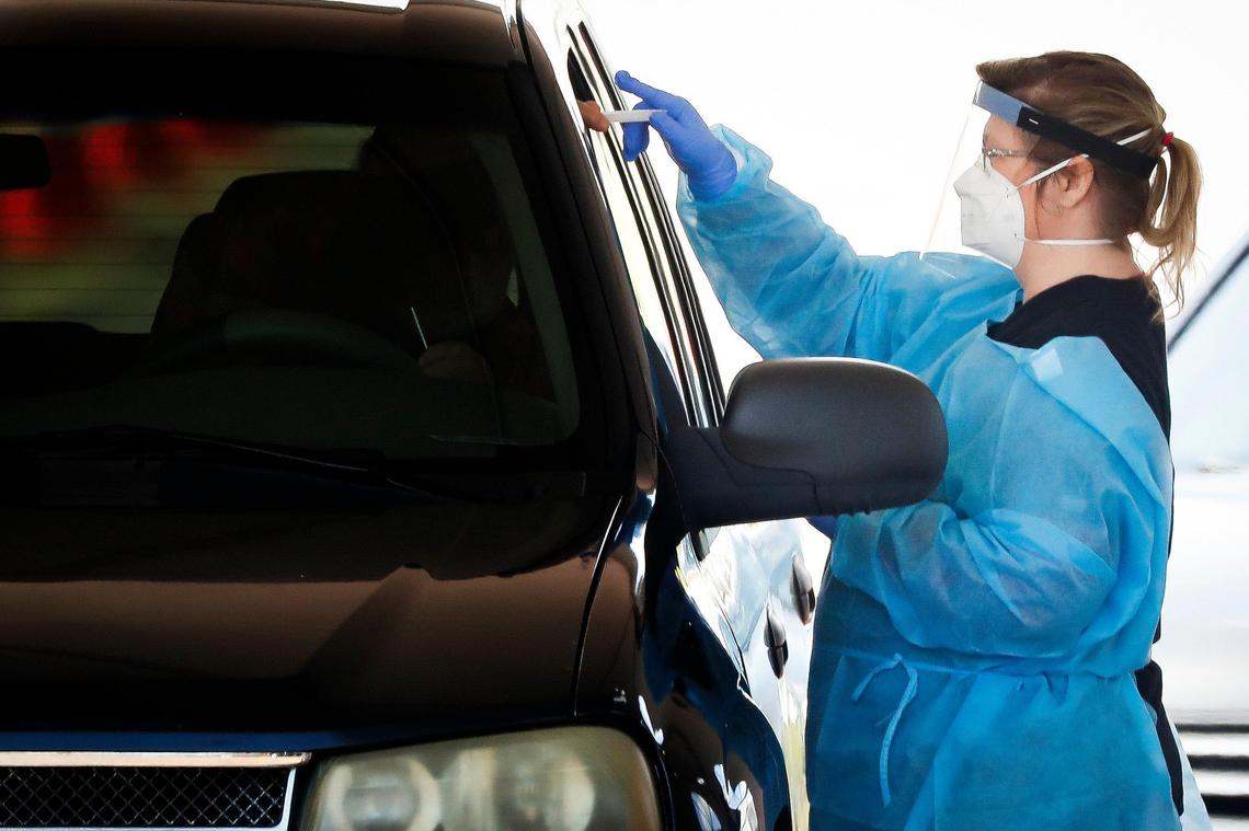 A healthcare worker takes a COVID-19 test from a patient at a drive-in testing site in the parking lot of the Center for Rural Development in Somerset, Ky., Tuesday, April 21, 2020.
