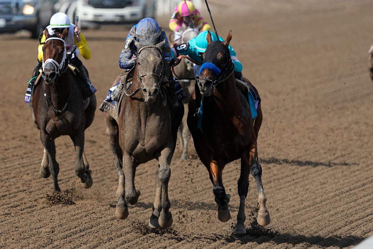 Junior Alvarado rides Cody’s Wish, center, as he leads Flavien Prat riding National Treasure, right, to win the Breeders’ Cup Dirt Mile on Saturday at Santa Anita Park.