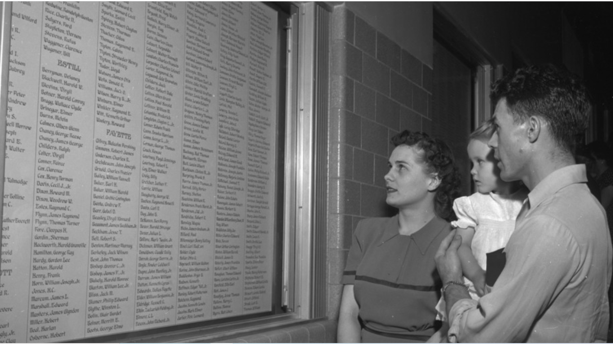 Viewers at Memorial Coliseum look at the names of soldiers lost in World War II that were hand inscribed by Professor John Horine.
