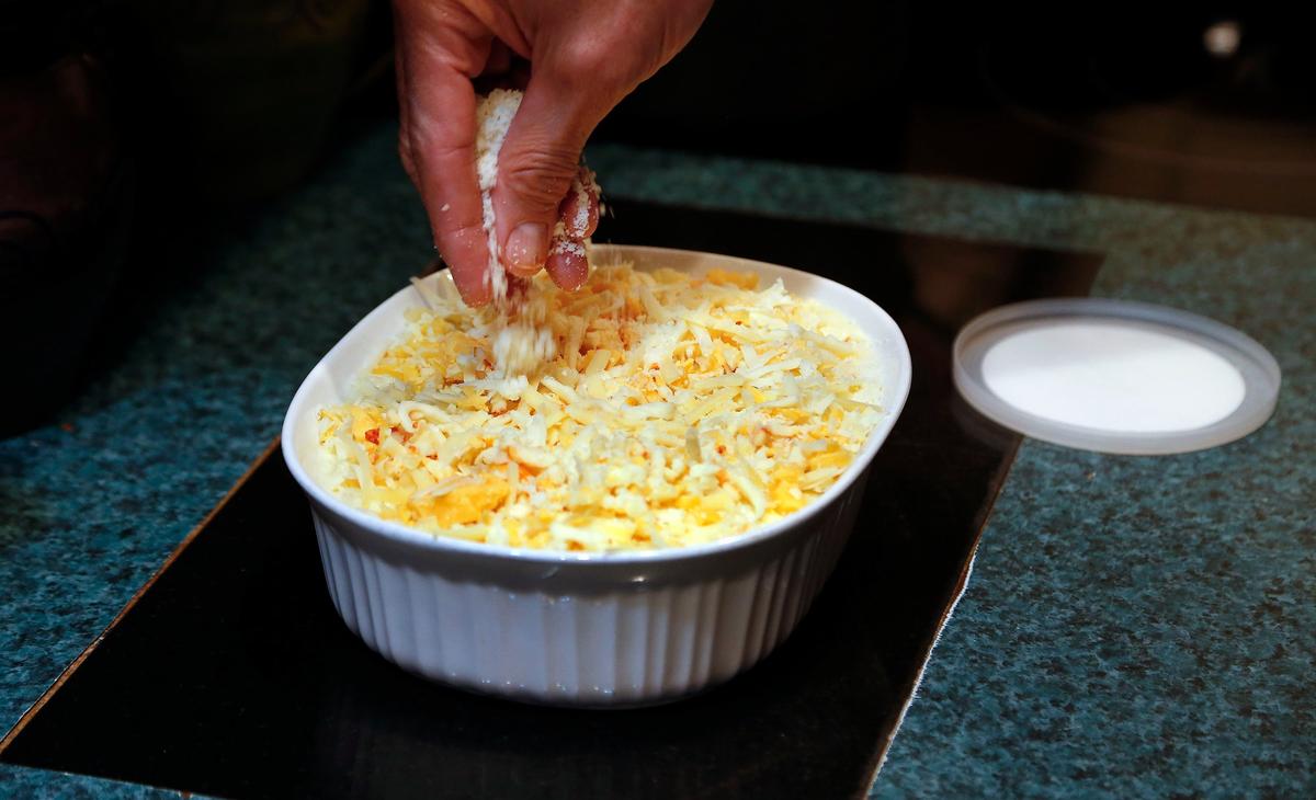 After he mixes the elbows and the cheese sauce, Kenny “Sky” Walker sprinkles on the rest of the cheese, and the grated pecorino romano on his macaroni and cheese before putting it in the oven.