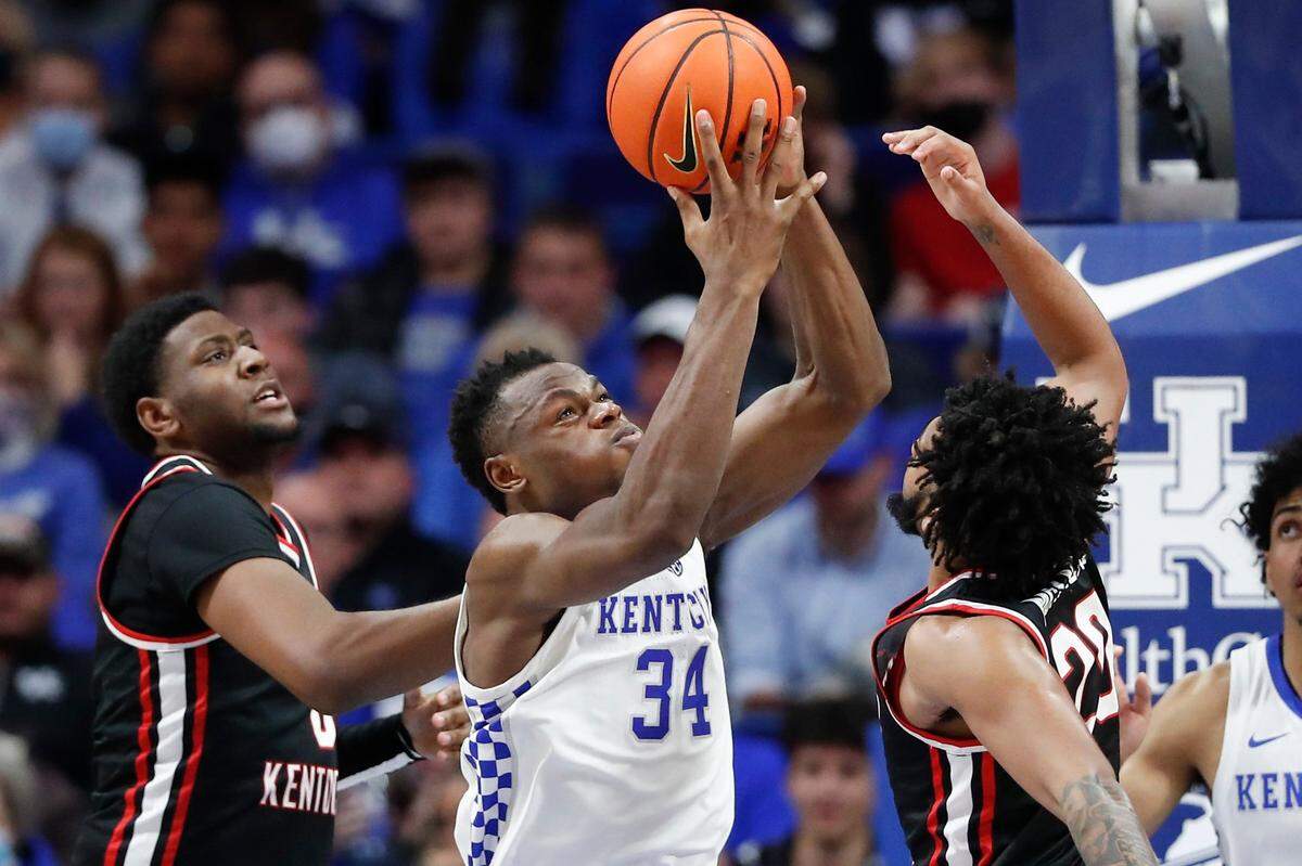 Kentucky Wildcats forward Oscar Tshiebwe (34) rebounds the ball over Western Kentucky Hilltoppers center Darrius Miles (0) and Western Kentucky Hilltoppers guard Dayvion McKnight (20) during a game at Rupp Arena in Lexington, Ky., Wednesday, Dec. 22, 2021.