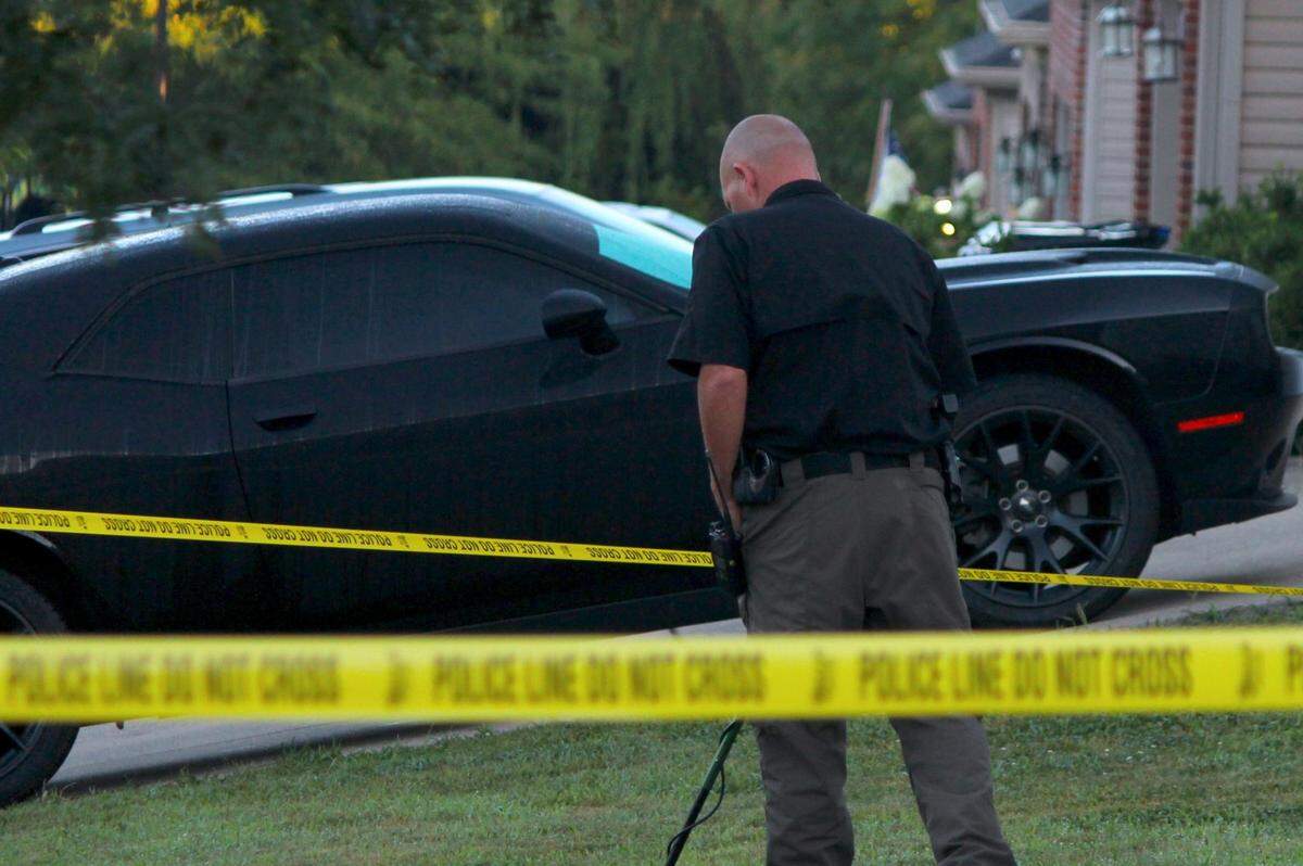 A Lexington police detective surveys a homicide scene with a metal detector at a home on the 3200 block of Creek Path Lane on Aug. 15, 2023.
