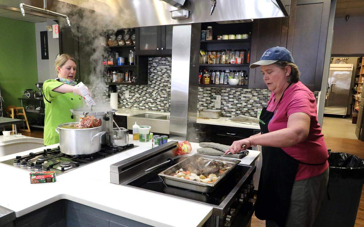Wild Thyme Cooking owner Allison Davis, left, and executive chef Shawn Caudill prepare family meals April 22 of pot roast, potatoes, green beans and carrots with biscuits. The cooking class and caterer offers a different family style meal a day.