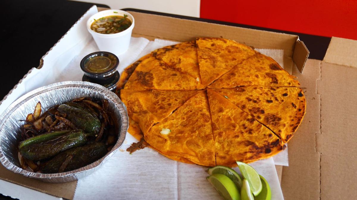 The Quesa-Pizza at El Cid is made with barbacoa meat, cheese, cilantro and chopped onions and served with consomme, tomatillo-based hot sauce, lime wedges and sauteed grilled jalapenos.
