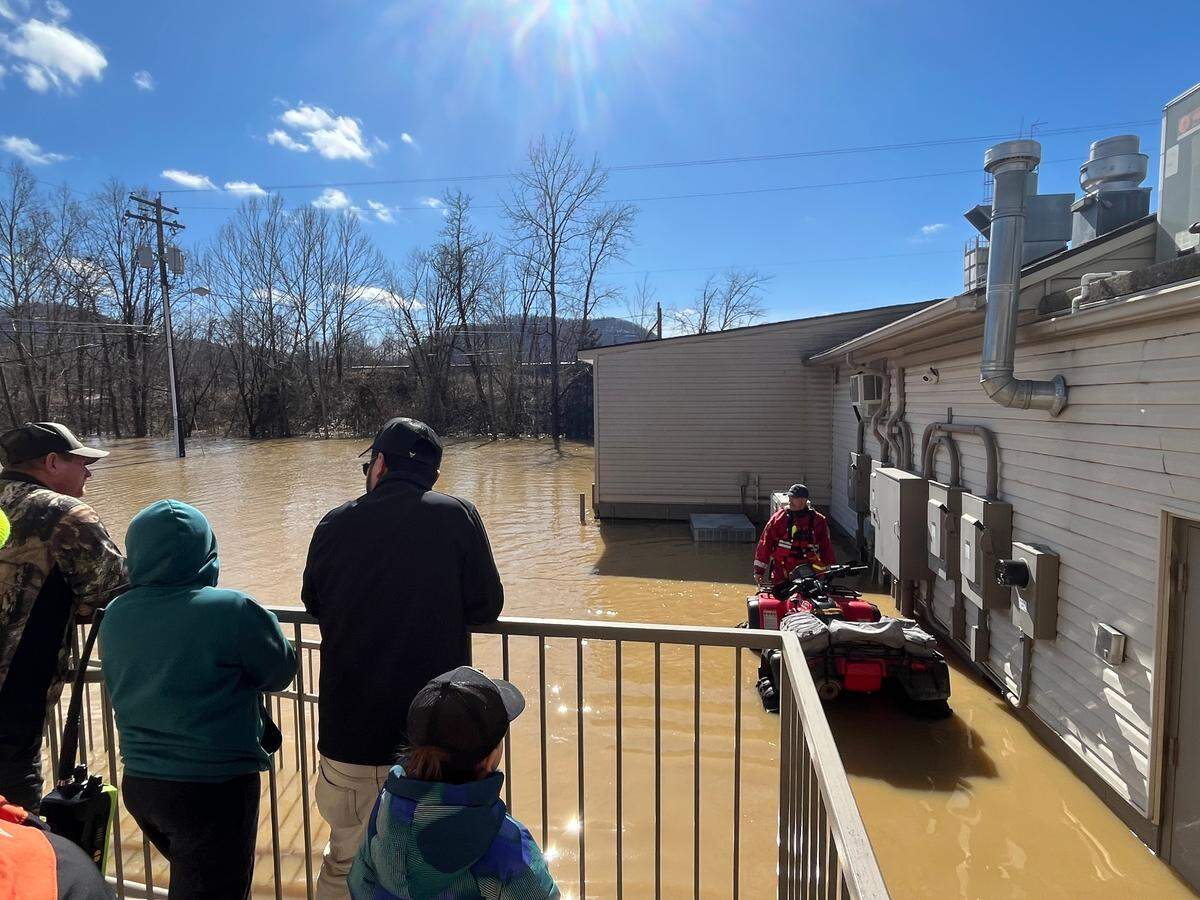 Julio Huerta, center, looks out from the back of his El Ranchito Restaurant with his sons Robert and Cesar while an emergency response worker attempts to move their ATV.
