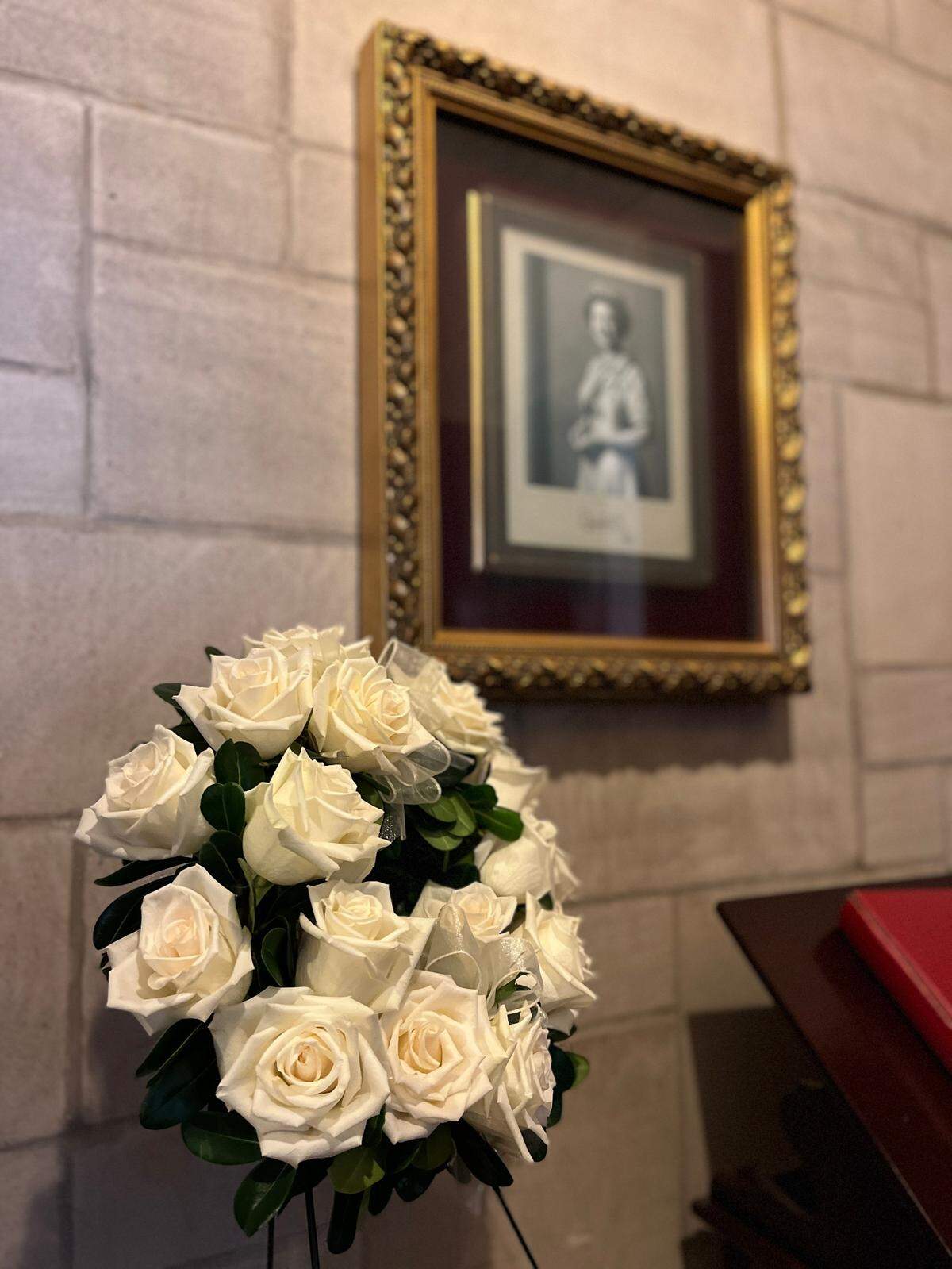A photo of Queen Elizabeth II hangs outside the chapel at St. John’s Episcopal Church in Versailles. The queen attended a worship service at the church during a visit to Kentucky in 1986. On the Sunday after her passing, a white wreath was placed in her honor.
