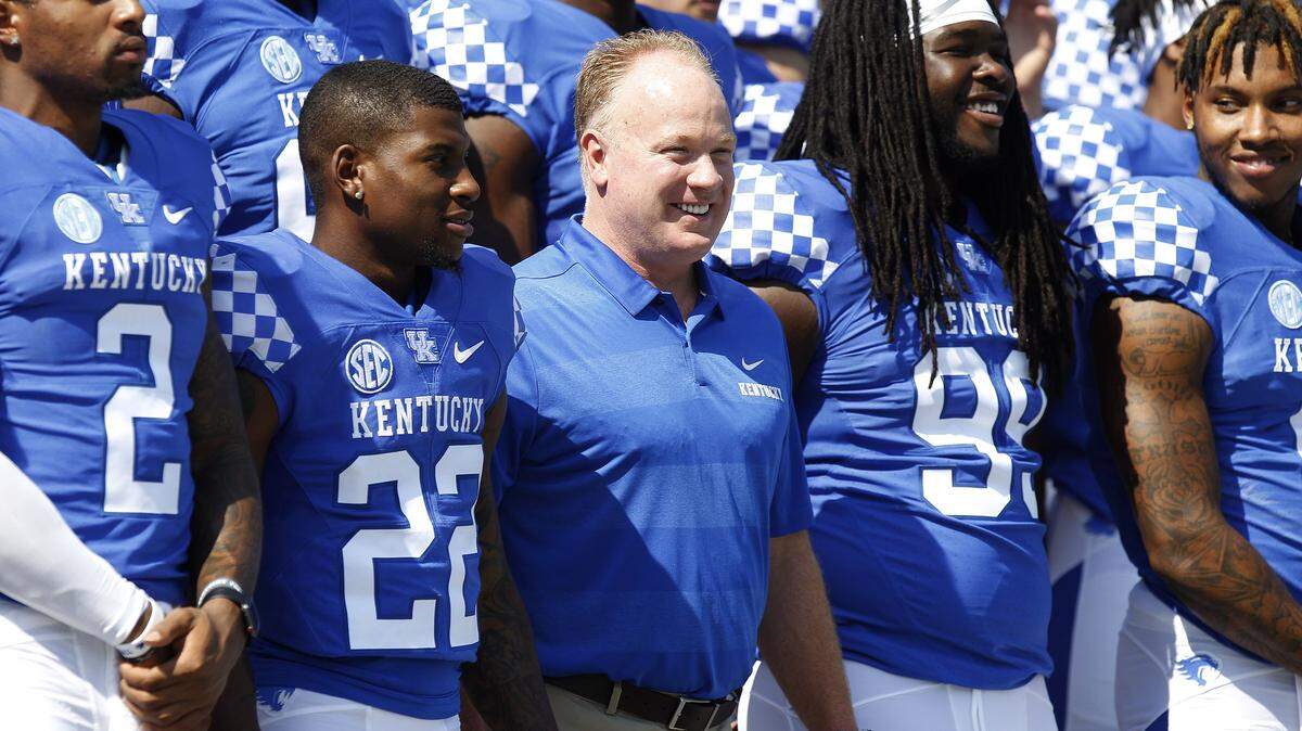 Coach Mark Stoops posed for the annual team picture between running back Sihiem King (22) and defensive lineman Adrian Middleton (99).