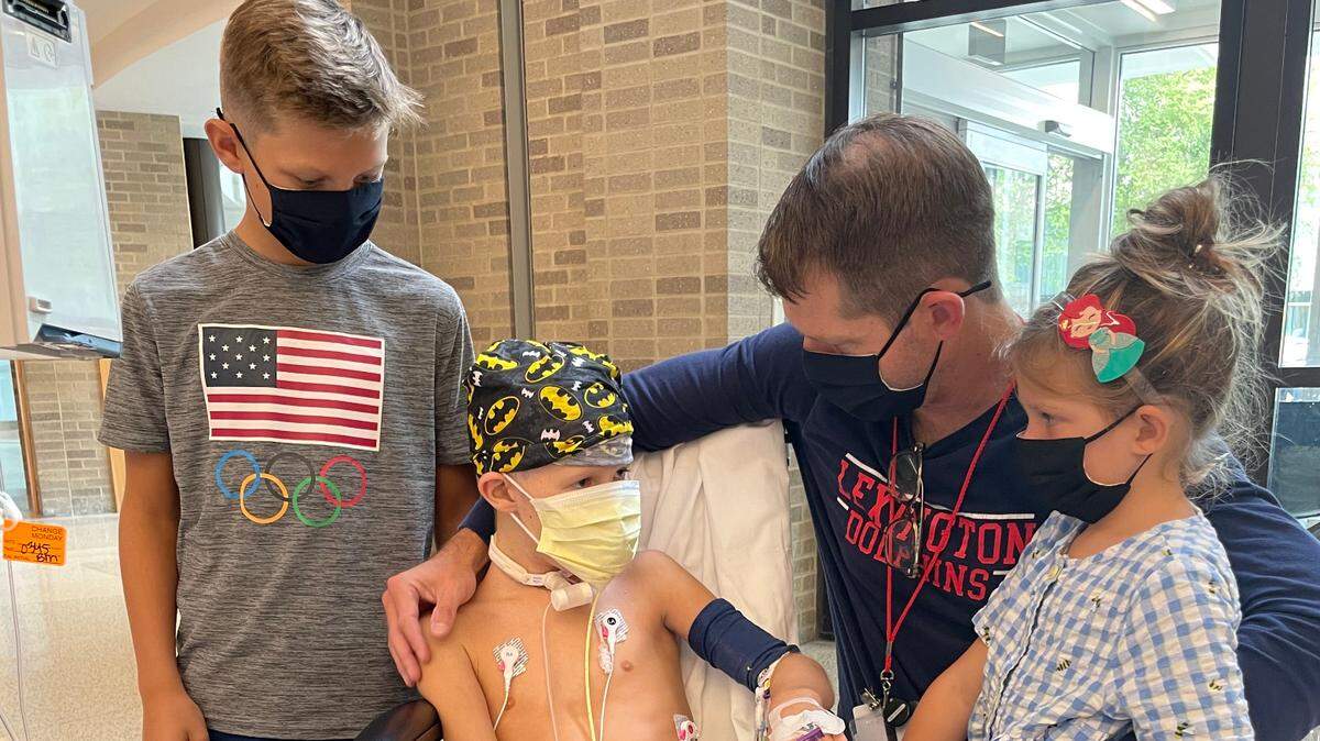 Robbie Messer, 8, of Lexington, sees his brother Mac and sister Eli for the first time in three weeks when they visited him earlier this month at Cincinnati Children’s Hospital Medical Center. Robbie’s father Will Messer is also in the photo.