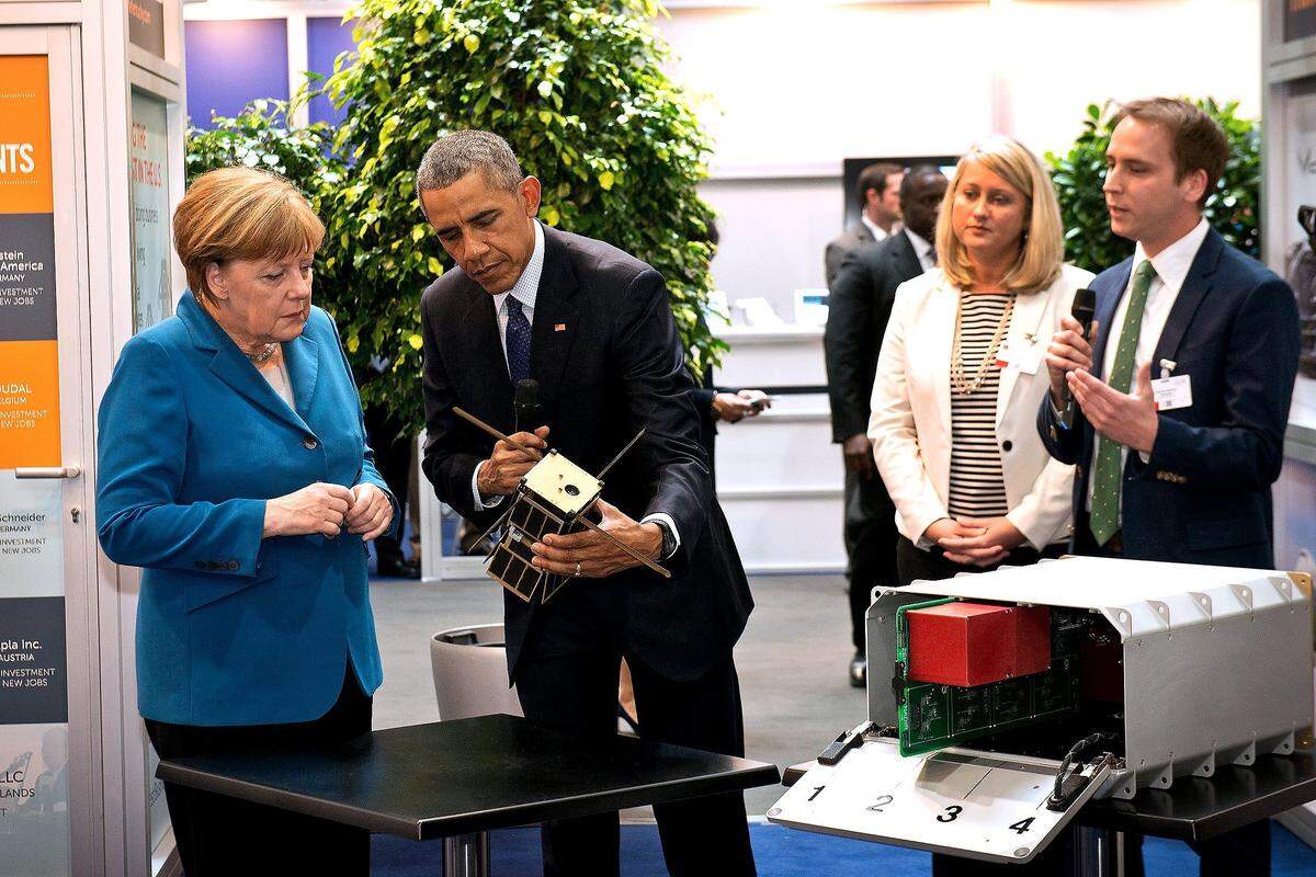 Space Tango CEO Twyman Clements, right, explains the company's technology to President Barack Obama and German Chancellor Angela Merkel, who inspect a cube satellite, at the Hannover Messe technology trade show in Germany in April 2016.  Beside Clements is Kentucky Business Development Commissioner Mandy Lambert. 
