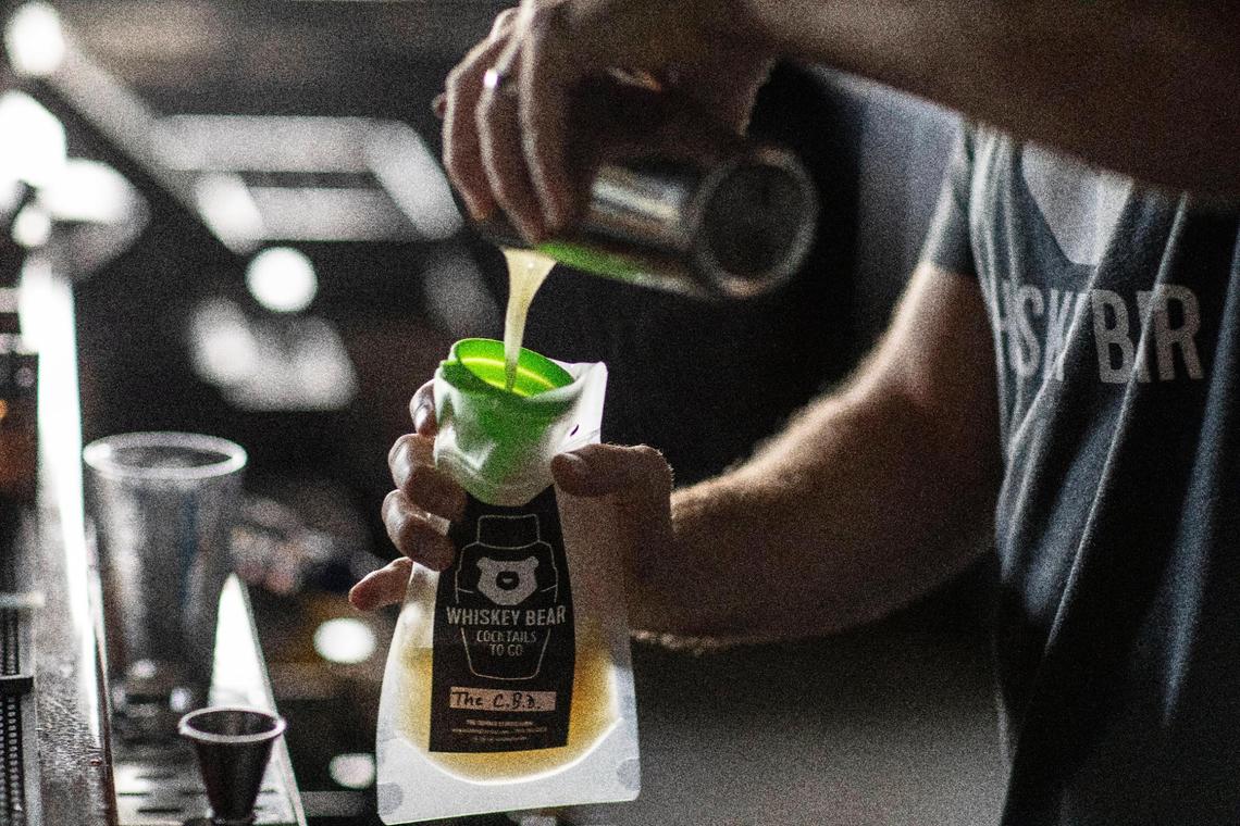 Daniel Marlowe, Whiskey Bear co-owner, pours The C.B.D., one of the bar’s most popular cocktails, into a to-go container Tuesday at the establishment at The Summit at Fritz Farm.