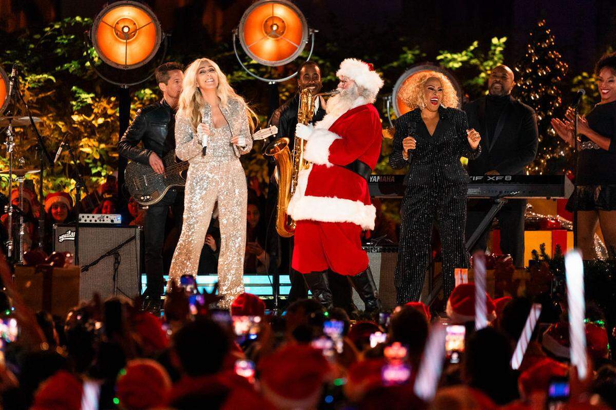 Cher and Darlene Love sing with a Santa playing a saxaphone during “Christmas in Rockefeller Center” on NBC.