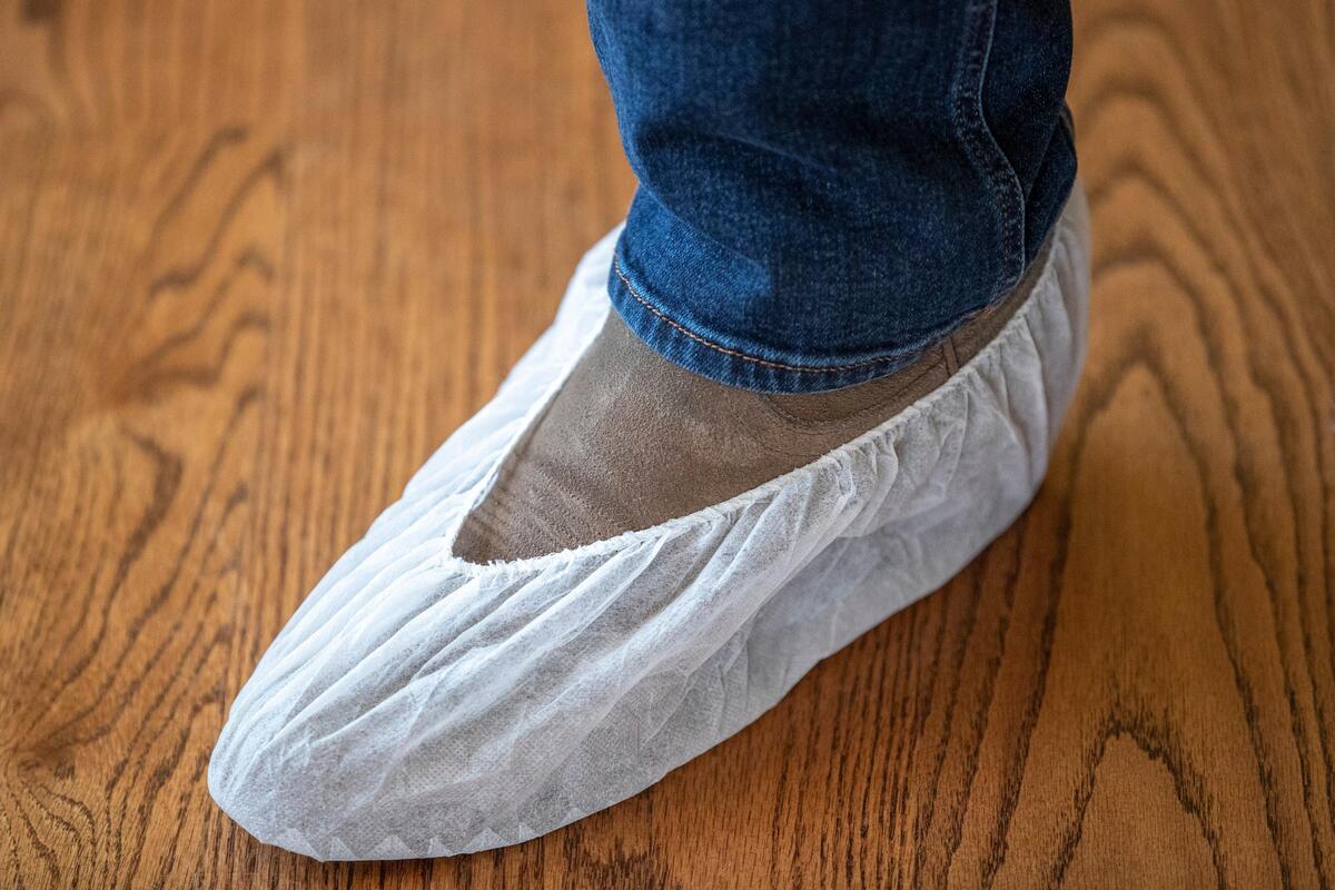 Real estate agent Rusty Underwood wears booties over his boots. Agents take only the potential buyer into a house and wear gloves and masks. They open doors for the potential buyers and avoid touching other surfaces.
