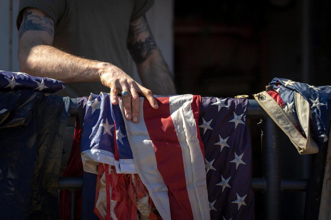National Guard Staff Sergeant Jonathan Jones holds an American flag while helping clean out the Three Forks Tradition office after severe flooding in downtown Beattyville, Ky, Wednesday, March 3, 2021.