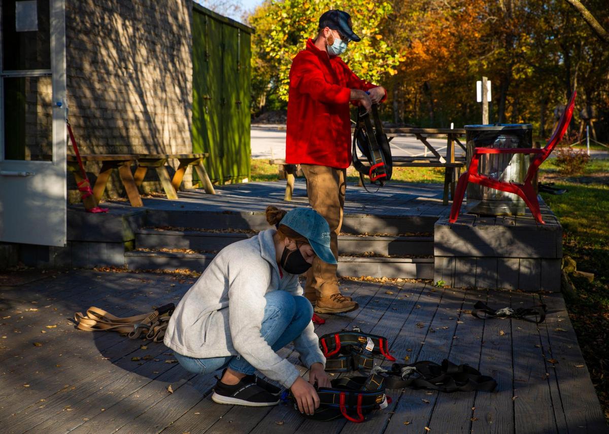 Jada McKenzie, a guide at Boone Creek Outdoors, (bottom) and Adam Downs, manager and guide, prepare gear for an upcoming zip line tour at Boone Creek Outdoors on Saturday, Oct. 17, 2020, in Lexington, Ky.