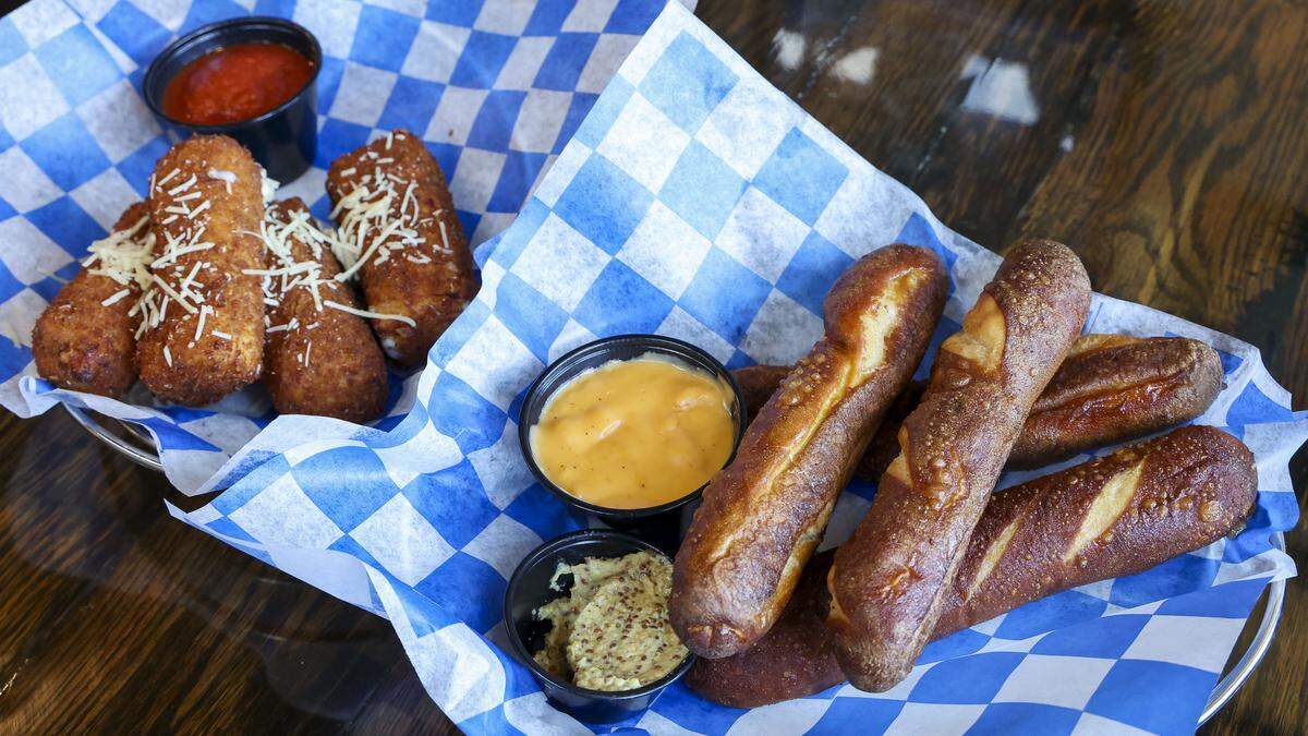 Two appetizer dishes from KSBar & Grille in Lexington, Ky., photographed Thursday, Aug. 28, 2025. At left is cheese logs ($15), which were a staple of the sports bar before a renovation and Bavarian Pretzel Sticks ($14), a new menu item.
