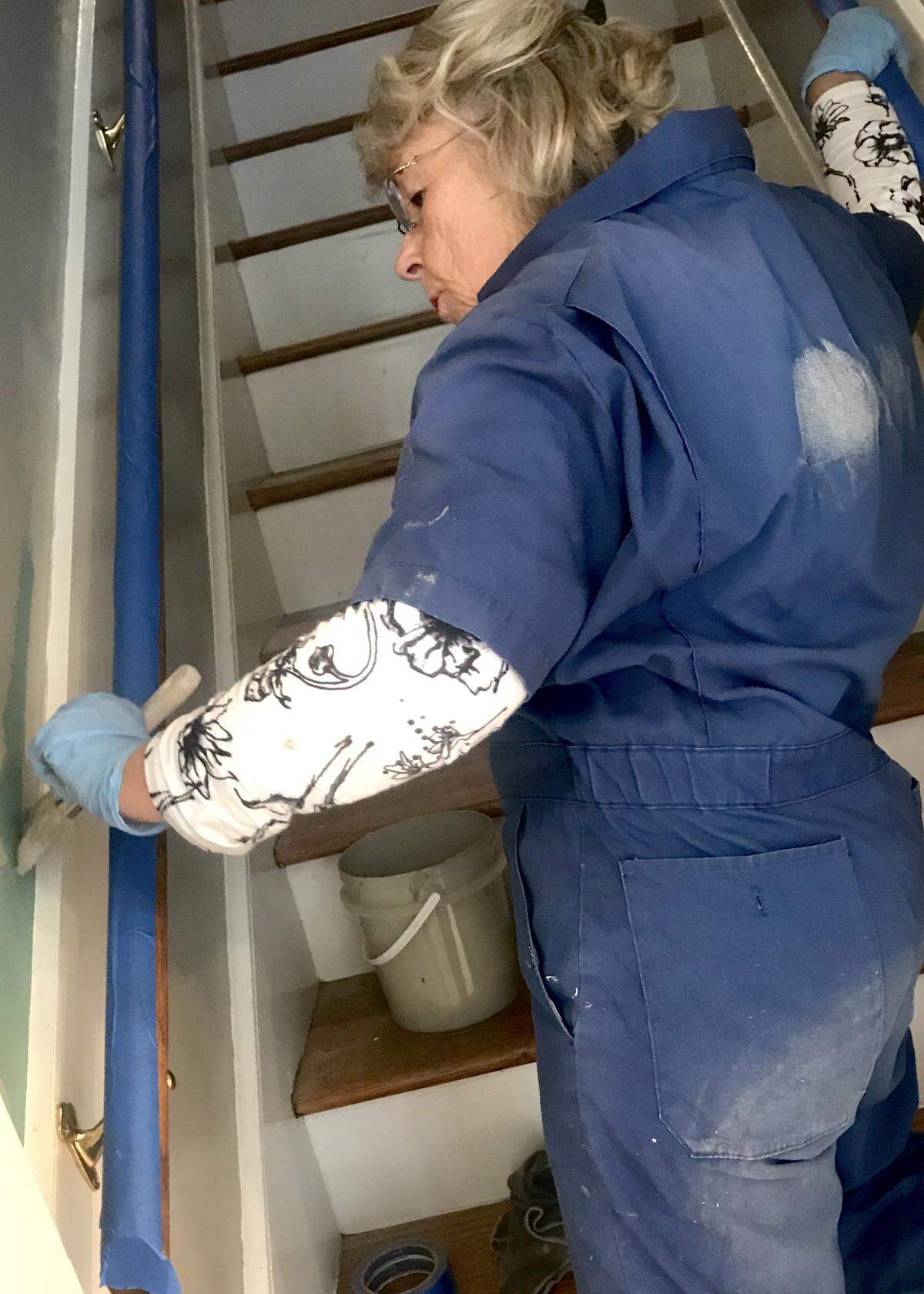 Event co-chair Kathy Thompson lends a hand to paint the back stairway.