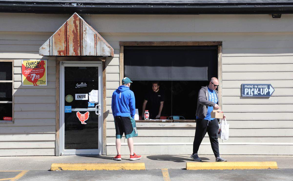 Eric Schneider, right, walked away in March with a carryout order from Joellas Hot Chicken. During the pandemic shutdown, the Cochran Road restaurant served patrons takeout through a dining room window.