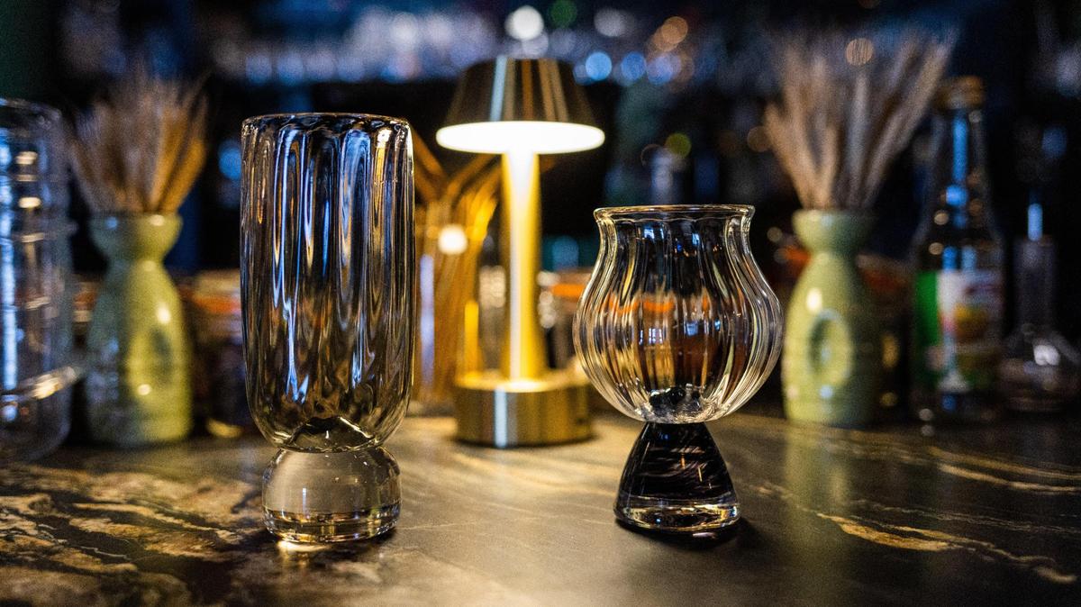 Two glass drinking cups made by glass artists of the Trifecta Glass Art Lounge on Walton Avenue and used for cocktails in the speakeasy lounge.